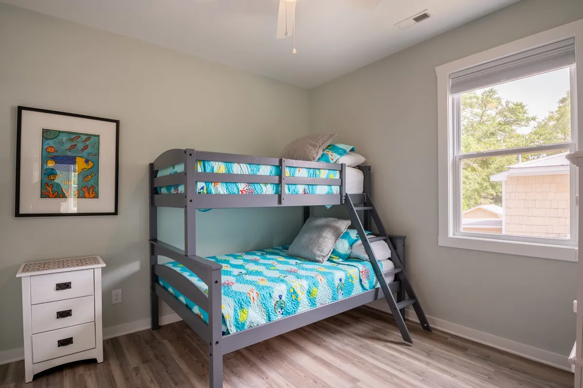 A playful, family-friendly bunk room featuring a colorful bunk bed, vivid bedding, cheerful artwork, and a nightstand. The arrangement encourages fun, togetherness, and bedtime stories, making it ideal for kids or families traveling together.