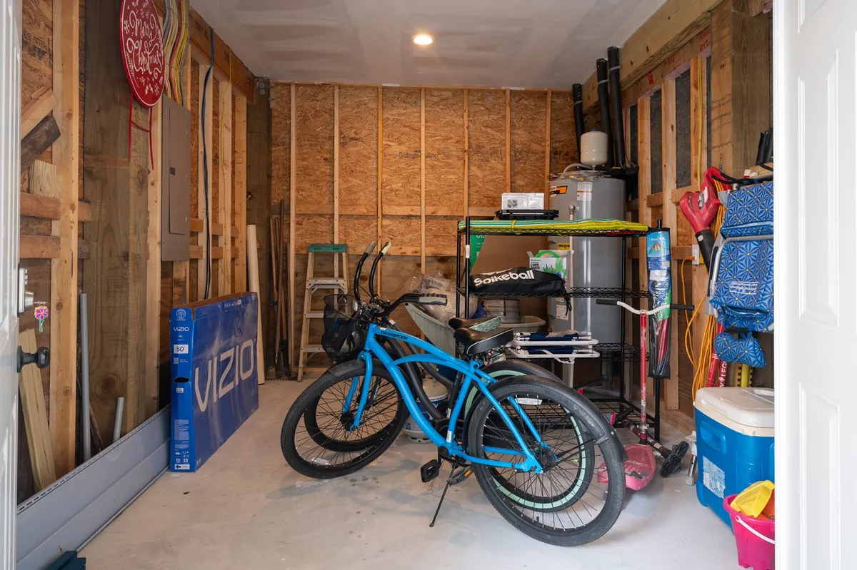 An organized interior space featuring blue bicycles, a workbench, and storage containers. The setup suggests readiness and ease for setting out on family bike rides to explore the local area, participate in group activities, or attend nearby festivals and events.